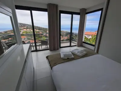 a bedroom with a white bed and large windows at Apartment Antonette in Calheta