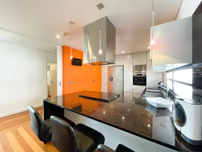 a kitchen with a black counter top and chairs at Casa Refúgio dos Canhas in Ponta do Sol