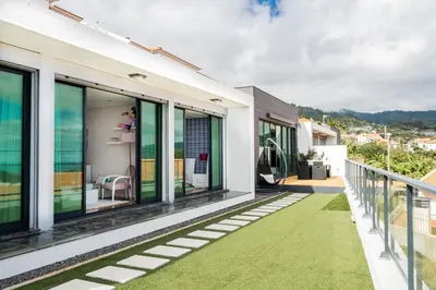 a house with a balcony with green grass at Casa Refúgio dos Canhas in Ponta do Sol