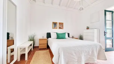 a white bedroom with a large bed and a desk at Nossa Casa by Casas dos Lebre in Porto Santo