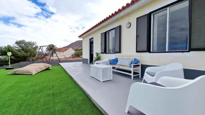 a patio with white chairs and a yard with green grass at Casa da Ponta by Casas dos Lebre in Porto Santo