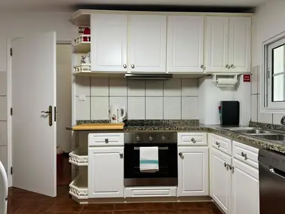 a kitchen with white cabinets and a black oven at Arco Apartment in Arco da Calheta