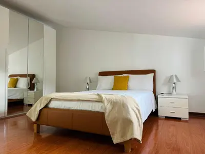 a white bedroom with a large bed with yellow pillows at Arco Apartment in Arco da Calheta