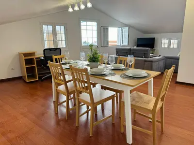 a dining table and chairs in a living room at Arco Apartment in Arco da Calheta
