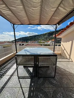 a table on the balcony of a house at Arco Apartment in Arco da Calheta