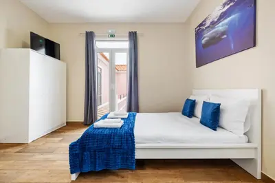 a bedroom with a white bed with blue pillows at A ver o mar rooms - Santa Cruz city center in Santa Cruz