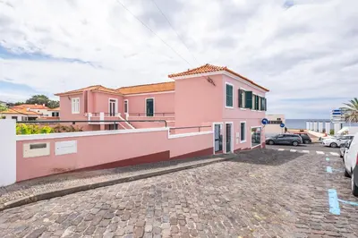 a pink house with the ocean in the background at A ver o mar rooms - Santa Cruz city center in Santa Cruz