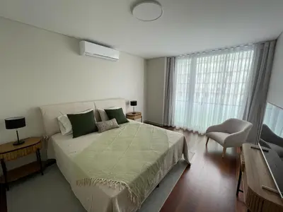 a white bedroom with a bed and a chair at Funchal Next Corner in Funchal