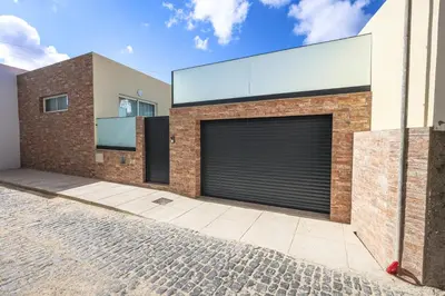 a brick building with a garage door on it at Casa do Beco do Barlavento in Vila Baleira
