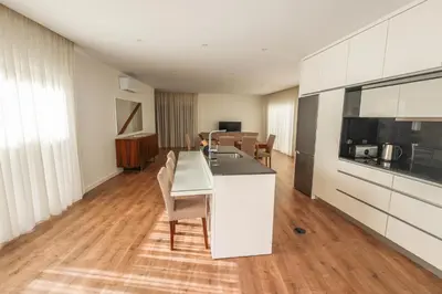 a kitchen with white cabinets and a table and chairs at Casa do Beco do Barlavento in Vila Baleira