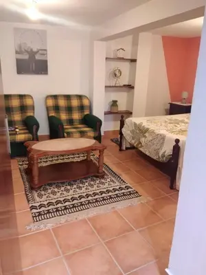 a bedroom with a bed and two chairs and a table at Casa Gama in Ribeira da Janela