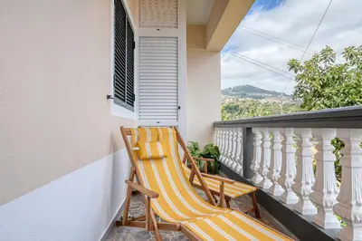 a pair of chairs sitting on the balcony of a house at Vale dos Amores, a Home in Madeira in Calheta