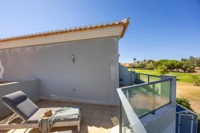 a balcony with a chair and a sliding glass door at Boa Vista - Golf View Villa in Lagos