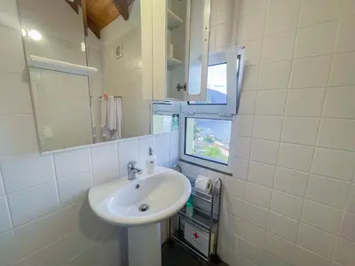 a white bathroom with a sink and a mirror at Palheiro do Farrobo in Porto Moniz