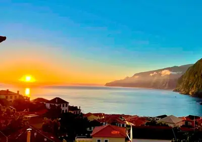 a view of a city and the ocean at sunset at Palheiro do Farrobo in Porto Moniz
