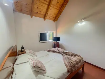 a small bedroom with a bed with two pillows at Palheiro do Farrobo in Porto Moniz