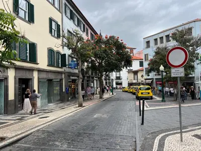 a city street with people walking and a yellow taxi at RC Flats Funchal D in Funchal