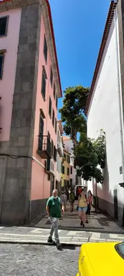 a man walking down a street in a city at RC Fltas Funchal C in Funchal
