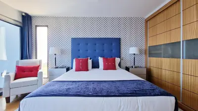 a bedroom with a large bed with a blue headboard and red pillows at Azure Serenity Villa by LovelyStay in Santa Cruz