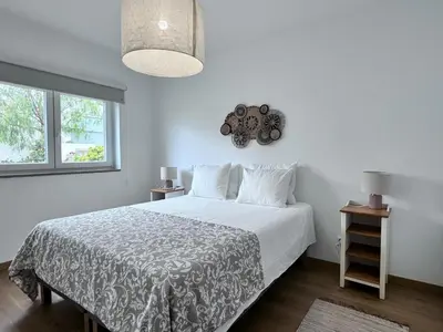a white bedroom with a large bed with a teddy bear on the wall at Luz Vila in Luz