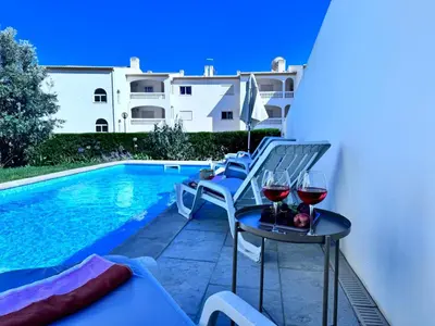 a patio with chairs and wine glasses next to a swimming pool at Luz Vila in Luz