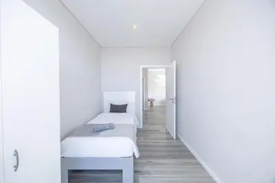a white bedroom with two beds and a hallway at Paradise Pereira House BY YOUR KEY MADEIRA in Calheta