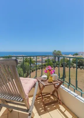 a deck with a table and a chair on a balcony at Casa dos Zefiros in Luz