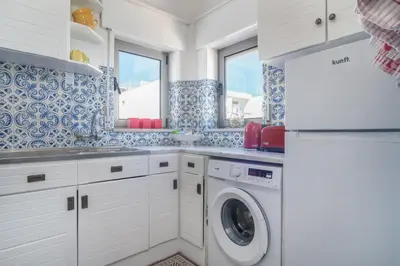 a kitchen with white cabinets and a washer and dryer at Casa dos Zefiros in Luz
