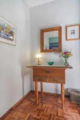 a table with a mirror and a vase of flowers on it at Casa dos Zefiros in Luz