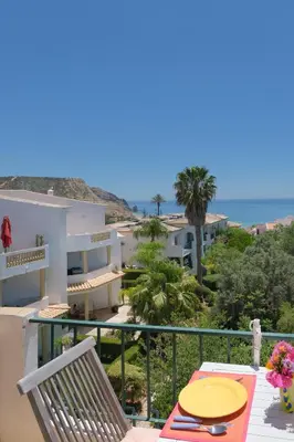 a balcony with a table and chairs and the ocean at Casa dos Zefiros in Luz