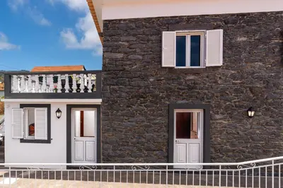 a stone house with a balcony on the side of it at Casa Silva, Calheta in Calheta