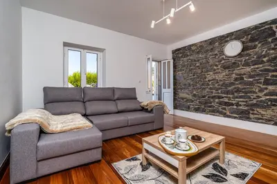 a living room with a couch and a stone wall at Casa Silva, Calheta in Calheta