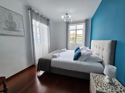 a bedroom with a large bed and a blue wall at Funchal Infinity View House by Rentallido in Funchal