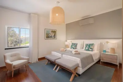 a bedroom with a bed and a chair and a window at OurMadeira - Bellissima in Estreito da Calheta