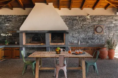 a kitchen with a table and chairs and a fireplace at OurMadeira - Bellissima in Estreito da Calheta