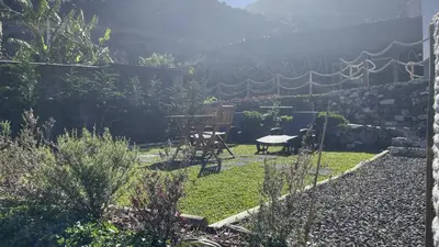 a patio with a table and chairs in a garden at Casas das Hortas, Apartamento Vista Mar in Seixal