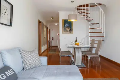a living room with a staircase and a table with chairs at VeBella Ocean View in Caniço
