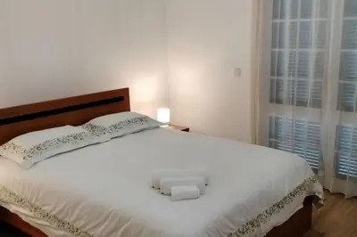 a bedroom with a white bed with a wooden headboard at Casa Neto Jardim in Calheta