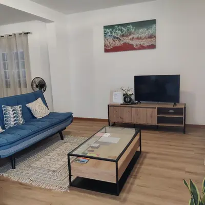 a living room with a blue couch and a tv at Casa Neto Jardim in Calheta