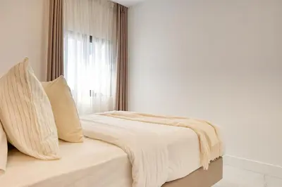 a white bedroom with a bed with a window at Beco Santa Emilia 1C, a Home in Madeira in Funchal