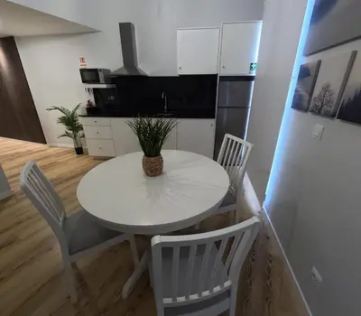 a kitchen with a white table and chairs and a refrigerator at Pretas Village Flats in Funchal