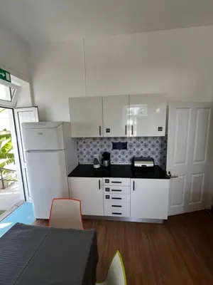 a kitchen with white cabinets and a black counter top at Lazareto 148 Hostel in Funchal