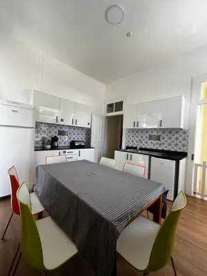 a kitchen with a table and chairs and a kitchen with white cabinets at Lazareto 148 Hostel in Funchal