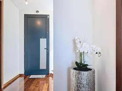 a vase of flowers in a hallway with a blue door at Villa Ribeiro Real 12 A in Câmara de Lobos