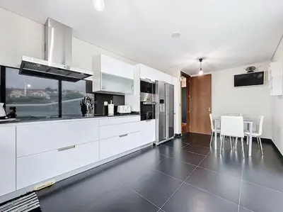 a kitchen with white cabinets and a table and chairs at Villa Ribeiro Real 12 A in Câmara de Lobos