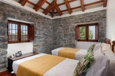 a bedroom with two beds and a stone wall at Villa Roque by An Island Apart in Calheta