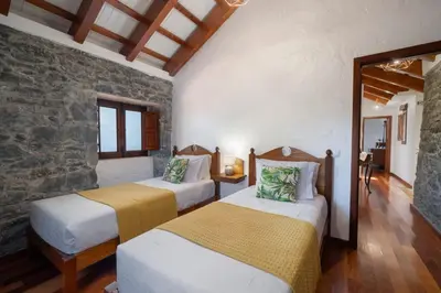 two beds in a room with a stone wall at Villa Roque by An Island Apart in Calheta