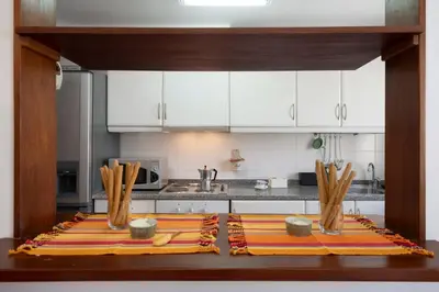 a kitchen with white cabinets and mats on a table at Apartamento Ilha Dourada by An Island Apart in Porto Santo