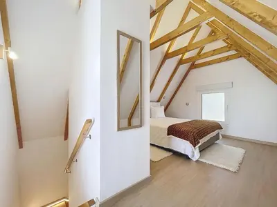 a bedroom in a loft with a bed and a mirror at Celeiro do Avô in Santana
