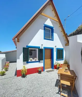 a house with blue windows and a patio at Celeiro do Avô in Santana